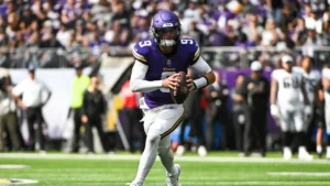 This image is about J.J. McCarthy, and he is runinig with ball