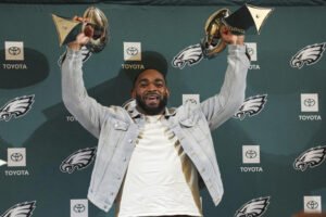 This image is about Brandon Graham celebrates with two trophies at an Eagles press conference.