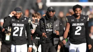 This image is about Deion Sanders walking with Colorado Buffaloes players during a game.