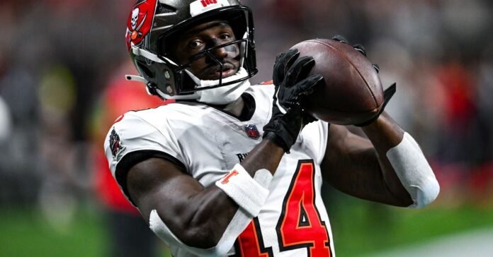 This image is about Chris Godwin catching a football in a Buccaneers jersey.